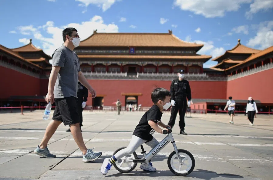 People wearing face masks walk in front of the entrance of the Forbidden City, while the closing of the Chinese People's Political Consultative Conference takes place in Beijing, 27 May 2020. (Noel Celis/AFP)