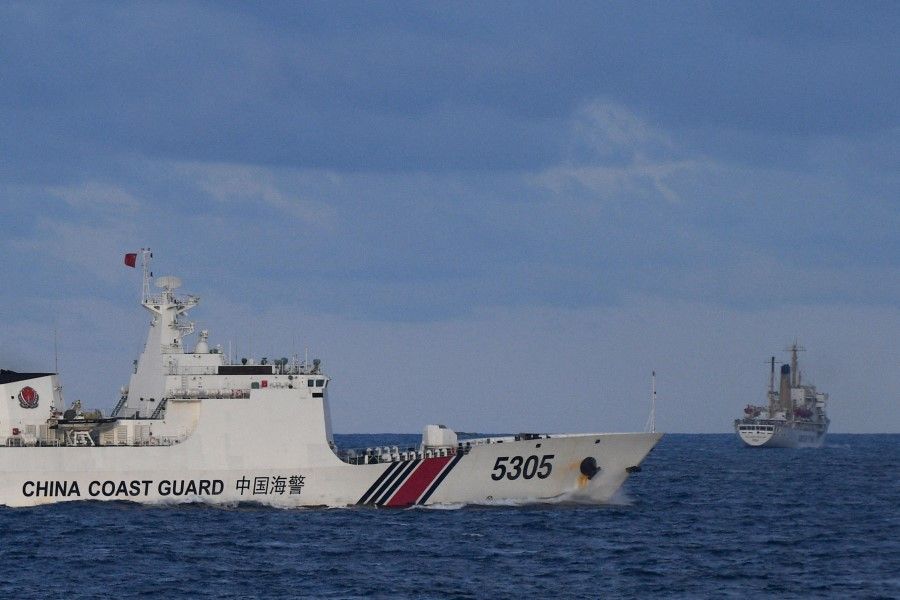 A Chinese Coast Guard ship sails near a Philippine vessel (right) that was part of a convoy of civilian boats in the disputed South China Sea on 10 December 2023. (Ted Aljibe/AFP)
