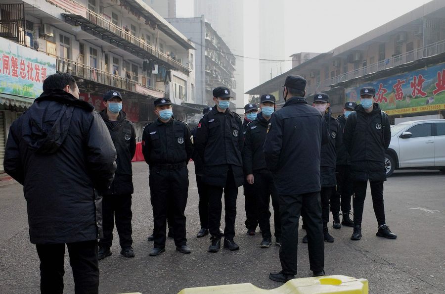 In this file photograph taken on 11 January 2020, security guards stand in front of the closed Huanan Seafood Wholesale Market, where health authorities say a man who died from a respiratory illness had purchased goods from. (Noel Celis/AFP)