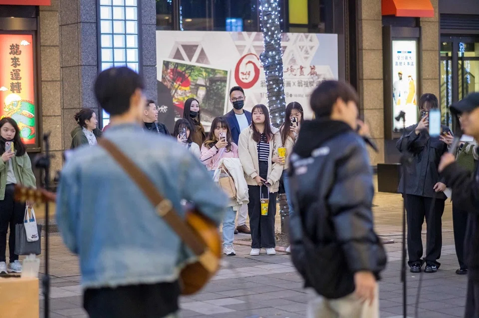 People watch street entertainers singing on a street at the Xinyi district in Taipei on 16 January 2024. (Sam Yeh/AFP)