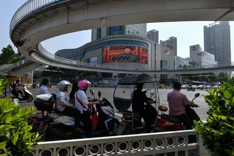 People watch a large screen showing Chinese President Xi Jinping giving a speech during celebrations to mark the 100th anniversary of the founding of the Communist Party of China in Fuyang, Anhui province, China on 1 July 2021. (STR/AFP)