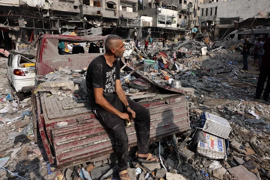 A man sits amid the destruction following Israeli strikes on Al-Shatee camp in Gaza City on 28 October 2023. (Mohammed Abed/AFP)