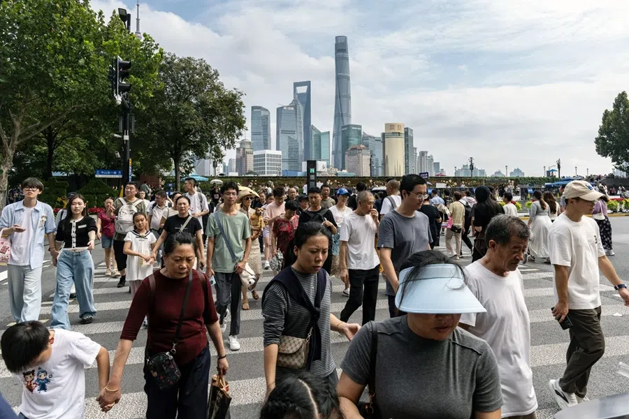 Pedestrians cross a road in the Bund in front of buildings in Pudong's Lujiazui Financial District during the Golden Week holiday in Shanghai, China, on 2 October 2025.