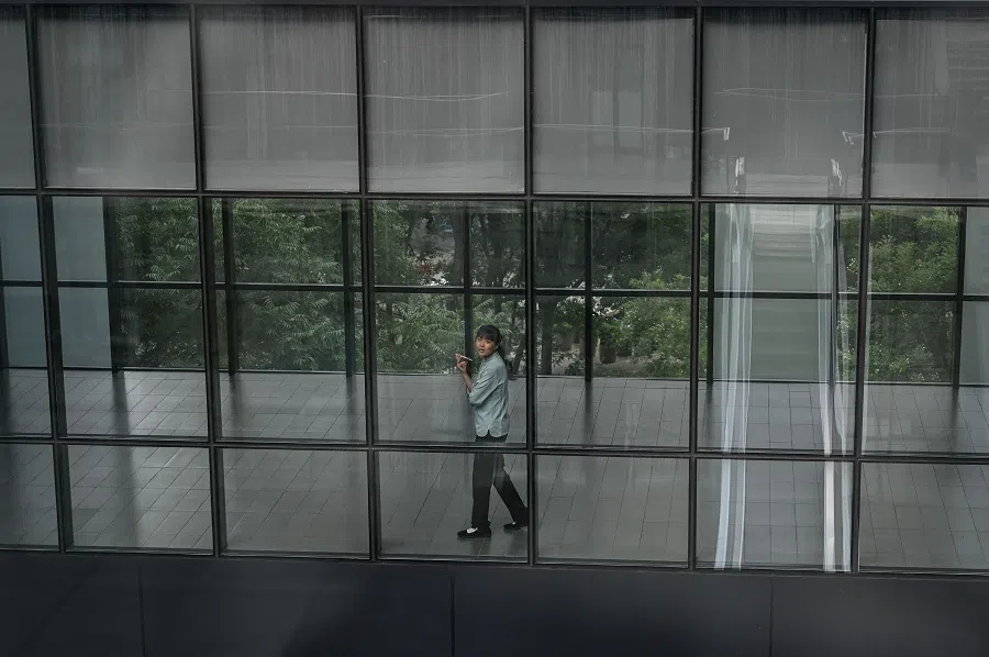 A woman talks on her phone at an office building in Beijing on 1 August 2024. (Jade Gao/AFP)