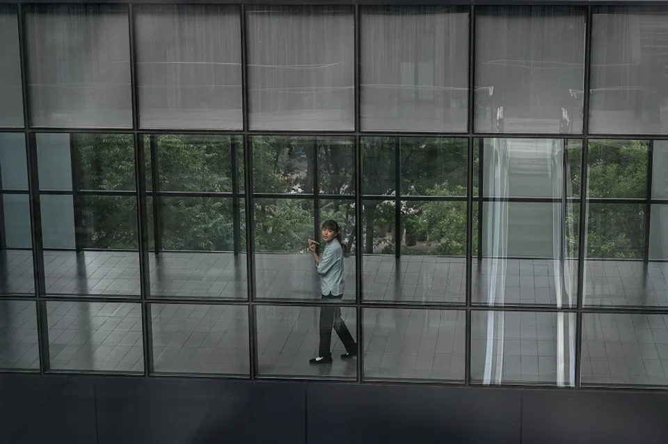 A woman talks on her phone at an office building in Beijing on 1 August 2024. (Jade Gao/AFP)