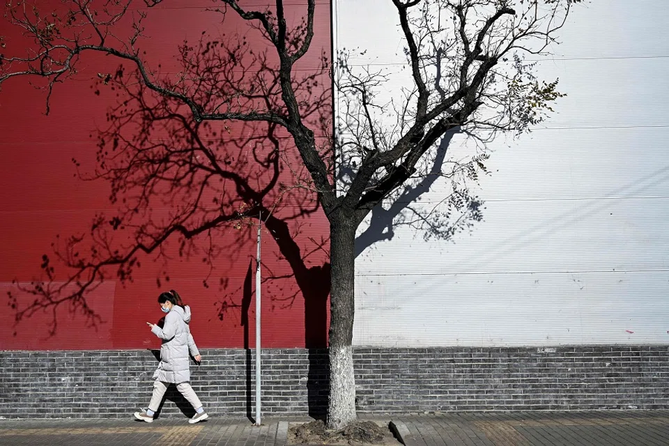 A woman walks past a tree on a street in Beijing on 23 November 2021. (Jade Gao/AFP)