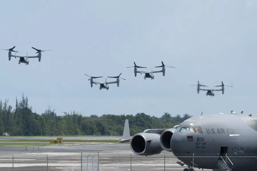 Osprey helicopters fly as a US Air Force C-17A Globemaster aircraft is seen on the ground after landing at Luis Muñoz Marín International Airport in Carolina, Puerto Rico, on 8 September 2025. (Jaydee Lee Serrano/AFP)