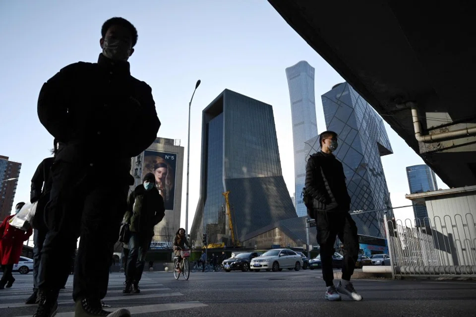 People cross a road in the central business district in Beijing on 16 December 2021. (Greg Baker/AFP)