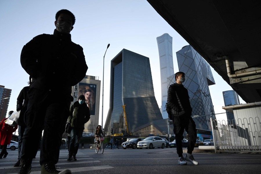 People cross a road in the central business district in Beijing on 16 December 2021. (Greg Baker/AFP)