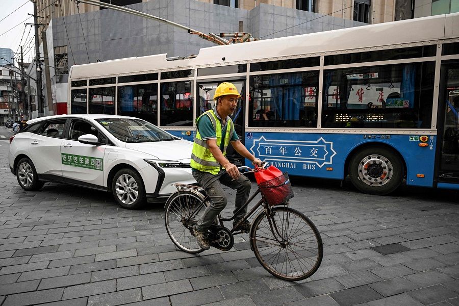 A worker rides a bicycle along a street past vehicles in the Huangpu district in Shanghai, China, on 15 June 2023. (Hector Retamal/AFP)