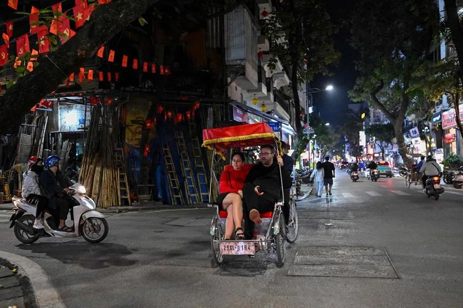 A couple rides on a cyclo bicycle taxi on a street in Hanoi on 20 November 2025. (Nhac Nguyen/AFP)