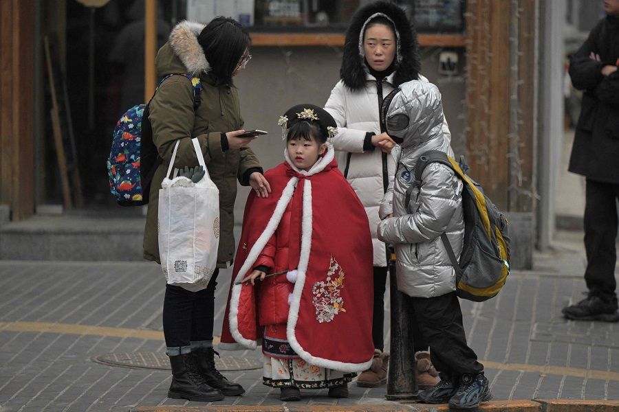 People are seen on a street in Beijing on 17 January 2024. (Pedro Pardo/AFP)