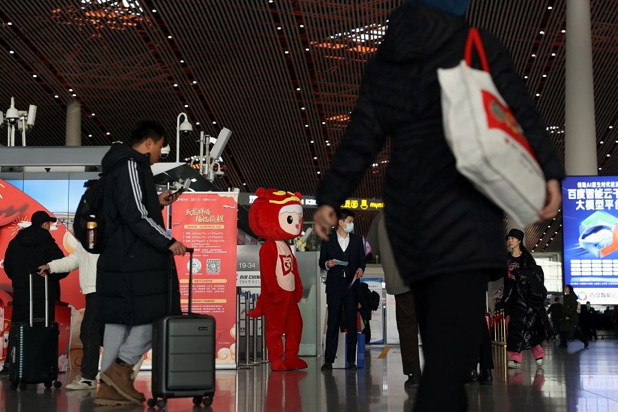 Travellers walk with their luggage at the Beijing Capital International Airport in Beijing, China, on 2 February 2024. (Florence Lo/Reuters)