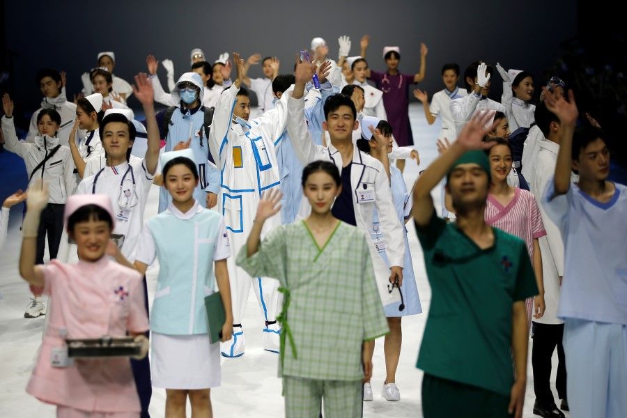 Models gesture as they present creations for medical professionals, which are designed by Beijing Institute of Fashion Technology in collaboration with Dishang, during China Fashion Week in Beijing, China, 11 September 2021. (Tingshu Wang/Reuters)