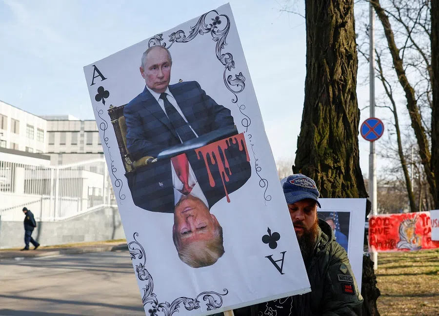 A demonstrator holds a banner depicting a playing card with portraits of Russian President Vladimir Putin and US President Donald Trump during a rally against Trump’s stance on the Russia-Ukraine war, amid Russia’s attack on Ukraine, in front of the US embassy in Kyiv, Ukraine, on 8 March 2025. (Valentyn Ogirenko/Reuters)