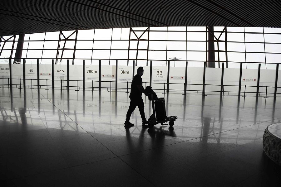 A lone passenger walks through the airport in Beijing on 18 June 2020. (Greg Baker/AFP)