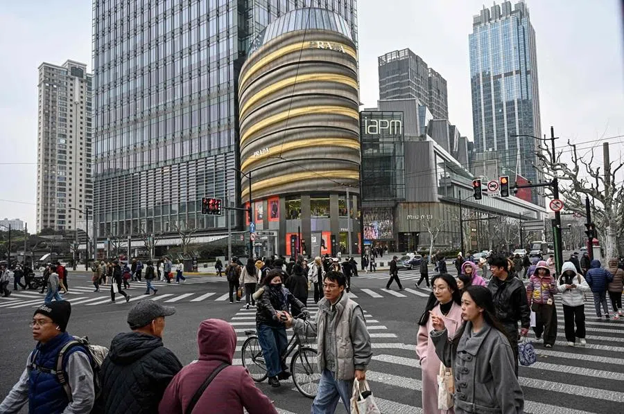 People cross a road in Shanghai, China, on 6 March 2026. (Jade Gao/AFP)