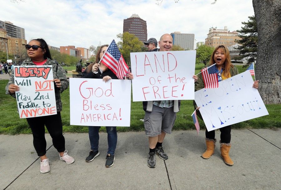 Protesters hold signs encouraging people to demand that businesses be allowed to open up, and people allowed to go back to work, at the Country Club Plaza on April 20, 2020 in Kansas City, Missouri. (Jamie Squire/AFP)