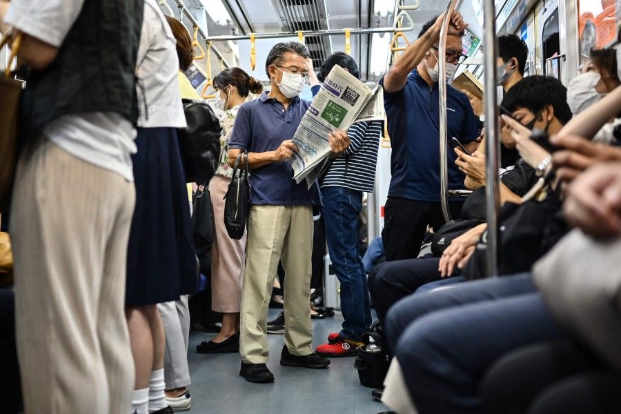 A man reads a newspaper while commuting on a train in Tokyo on 15 September 2020. (Charly Triballeau/AFP)