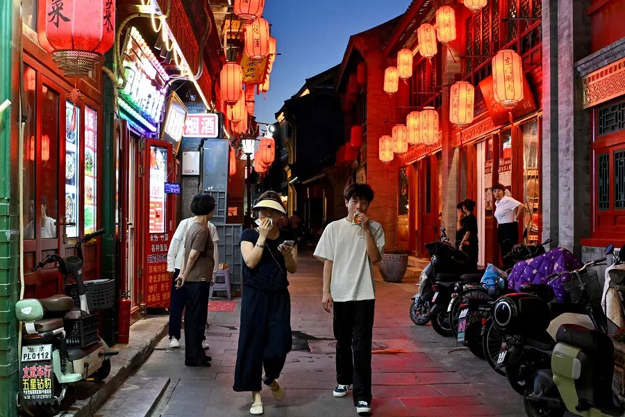 People walk along Qianmen promenade in Beijing on 5 July 2025. (Adek Berry/AFP)