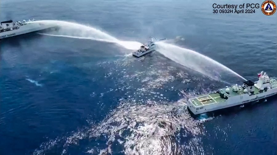 This frame grab from handout video footage taken and released on 30 April 2024 by the Philippine Coast Guard (PCG) shows the Philippine Coast Guard ship BRP Bagacay (centre) being hit by water cannon from Chinese coast guard vessels near the Chinese-controlled Scarborough shoal in disputed waters of the South China Sea.  (Handout/Philippine Coast Guard (PCG)/AFP)