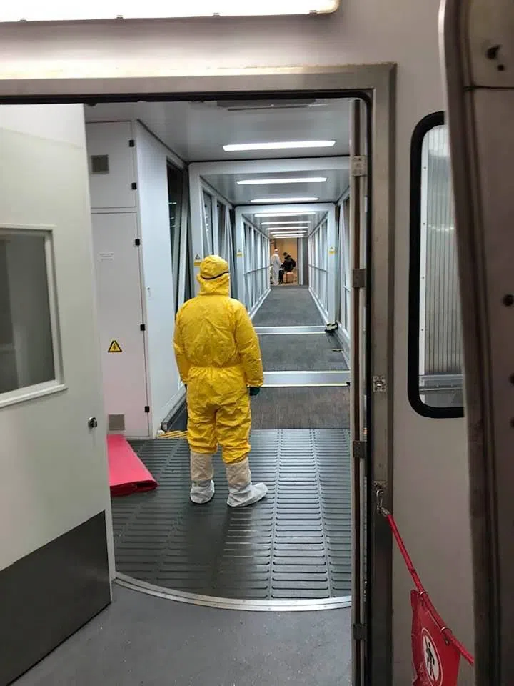 A worker in protective gear looks down the the walkway to a cargo plane at Wuhan Tianhe International Airport, February 2020. (Edward Wang via REUTERS)