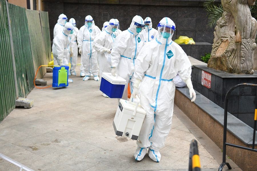 Medical workers in protective suits enter a residential compound under lockdown for nucleic acid testing following new cases of the coronavirus disease in Changsha, Hunan province, China, 4 August 2021. (CNS photo via Reuters)