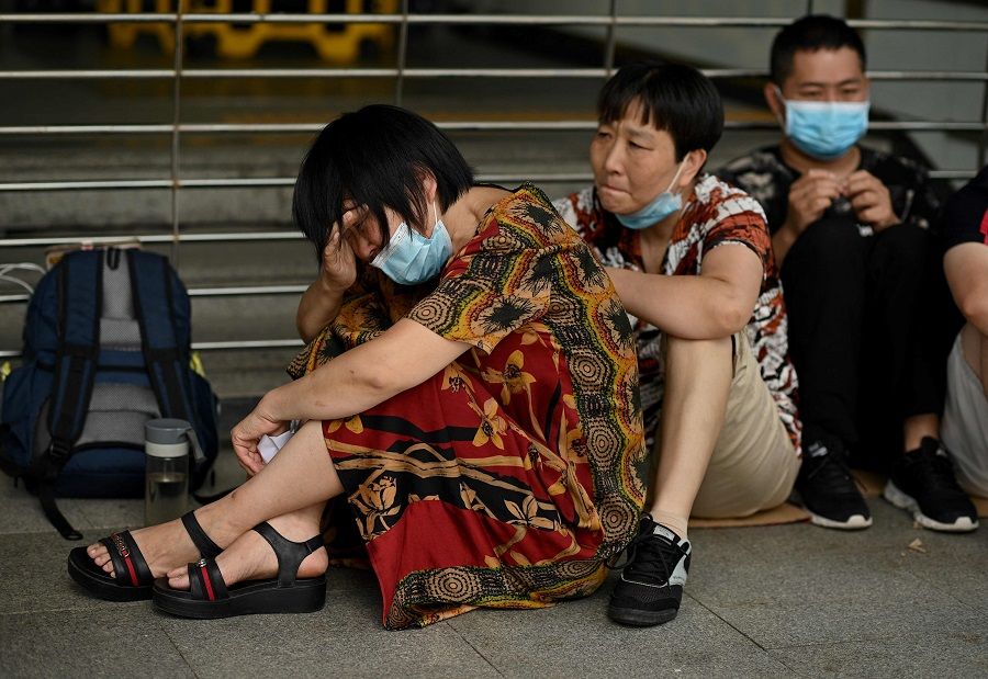 A woman cries as she and other people gather at Evergrande's headquarters in Shenzhen, China, on 16 September 2021. (Noel Celis/AFP)