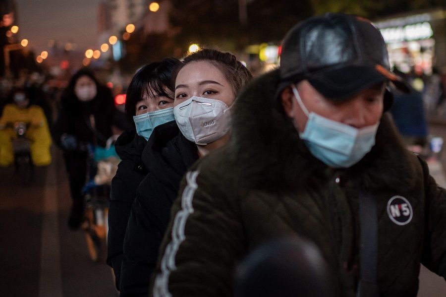 Women wearing face masks ride on a motorcycle during rush hour in Wuhan, Hubei, China, on 13 January 2021. (Nicolas Asfouri/AFP)