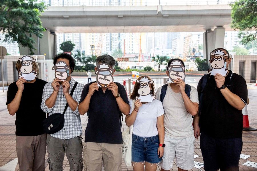 Supporters of a pro-democracy union pose with illustrations of sheep outside West Kowloon Court in Hong Kong on 23 July 2021, where members of the union face charges of sedition for publishing children's books which allegedly tried to explain the city's democracy movement using illustrations of sheep. (Isaac Lawrence/AFP)