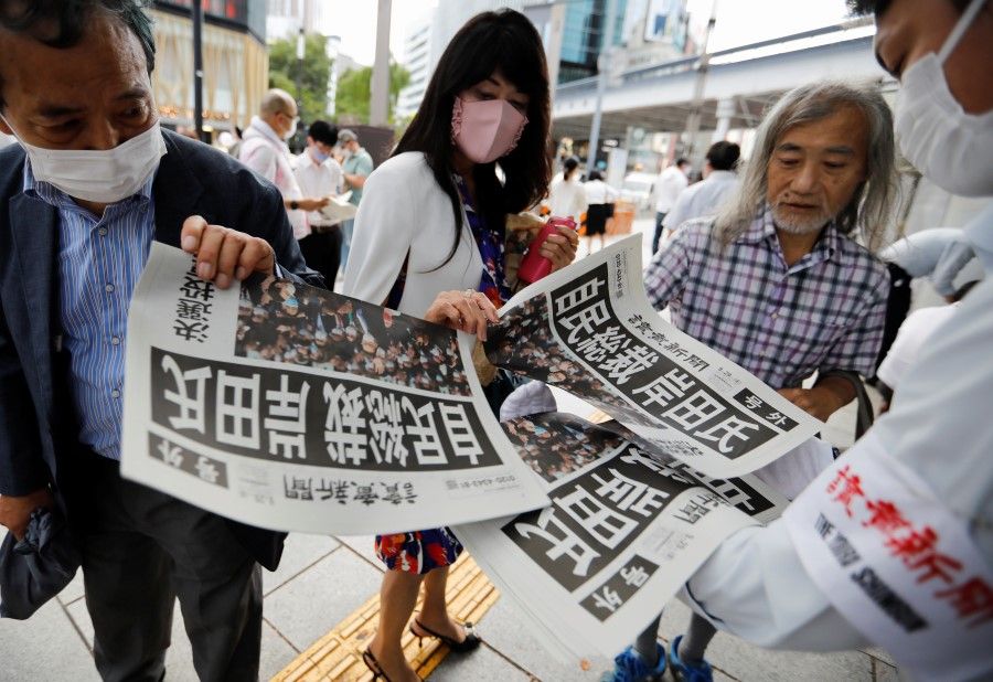 People receive extra editions of a newspaper reporting former Japanese Foreign Minister Fumio Kishida won in a ruling party leadership election, paving the way for him to replace Prime Minister Yoshihide Suga, amid the coronavirus disease (COVID-19) pandemic, in Tokyo, Japan, 29 September 2021. (Issei Kato/Reuters)