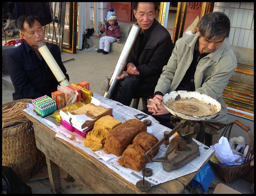 A stall selling tobacco at a market in rural Yunnan. Note the distinctive long smoking pipes used by the vendor's friends.