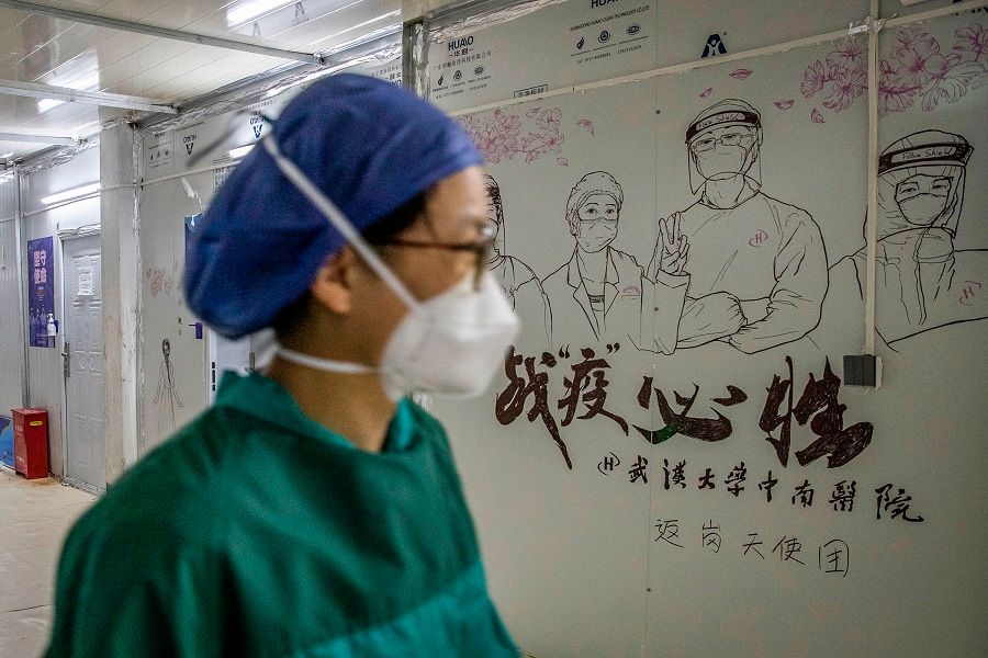 This photo taken on 14 April 2020 shows a staff member walking past graffiti encouraging people to defeat the Covid-19 coronavirus after all patients left Leishenshan Hospital in Wuhan, Hubei, China. (STR/AFP)