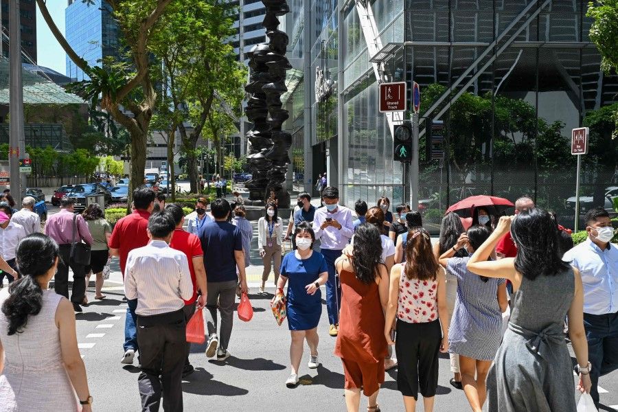 Office workers walk out for a lunch break at Raffles Place financial business district in Singapore on 10 May 2022. (Roslan Rahman/AFP)