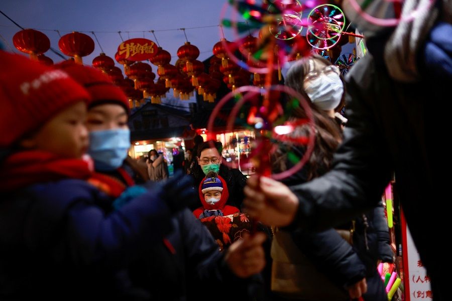 People stand with children in front of a souvenir shop in a historic part of Beijing, China, 14 February 2021. (Thomas Peter/Reuters)
