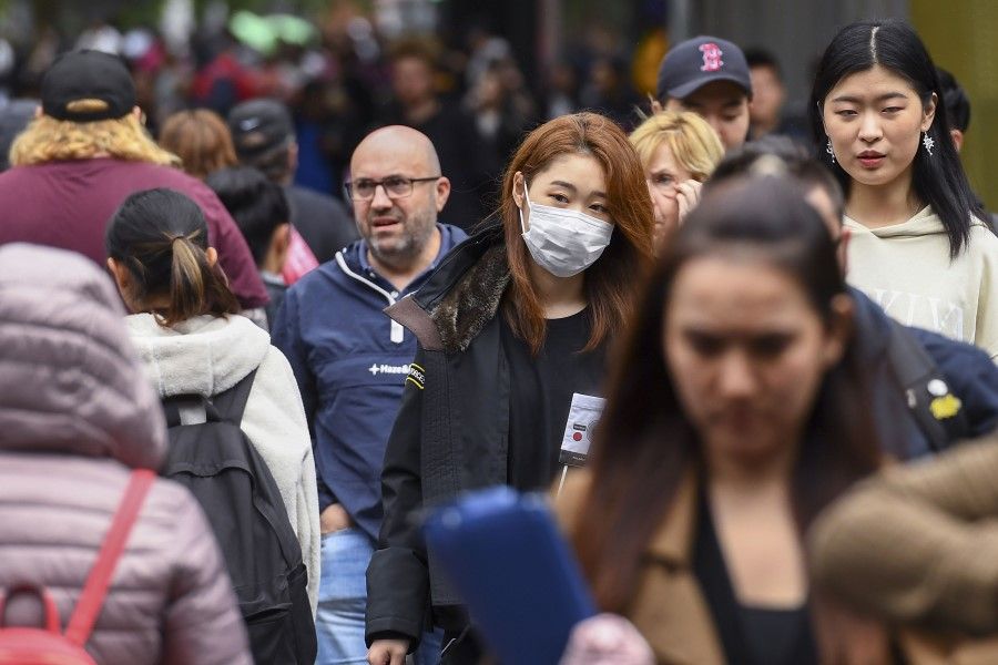 A woman wearing a face mask crosses the street in Melbourne, March 5, 2020. Australia has joined a number of countries calling for accountability from China for the coronavirus. (William West/AFP)