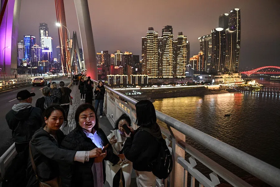 People walk on the Dongshuimen Bridge over the Yangtze River in Nan’an district, with Yuzhong district pictured in the background, in Chongqing, China, on 4 March 2025. (Hector Retamal/AFP)