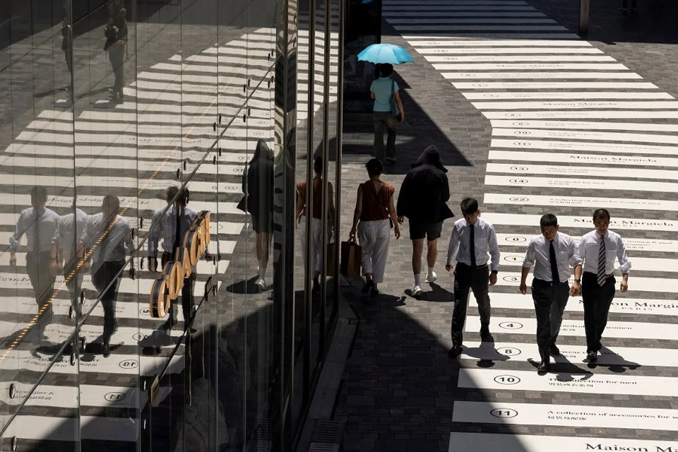 People walk in a shopping district in Beijing, China, on 14 July 2023. (Thomas Peter/Reuters)