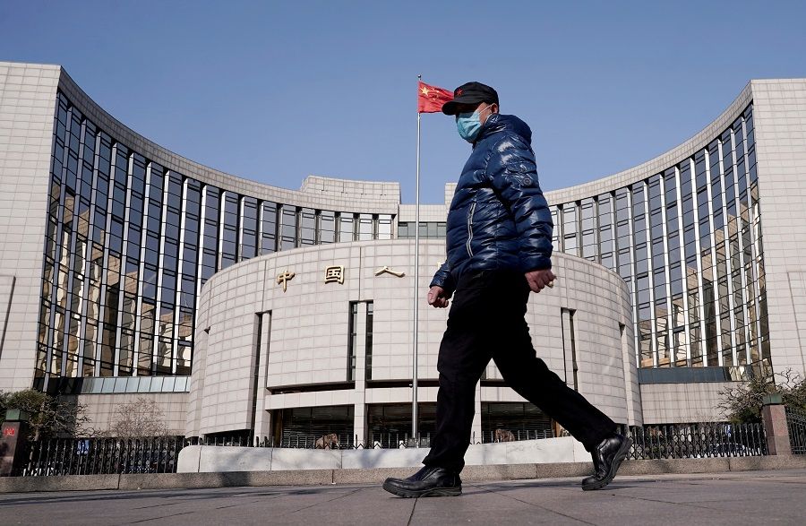 A man wearing a mask walks past the headquarters of the People's Bank of China, in Beijing, China, 3 February 2020. (Jason Lee/File Photo/Reuters)