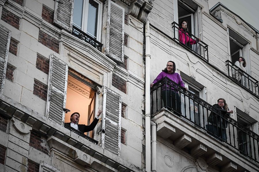 An opera tenor singer performs a song from his window in Paris on 26 March 2020. (Philippe Lopez/AFP)