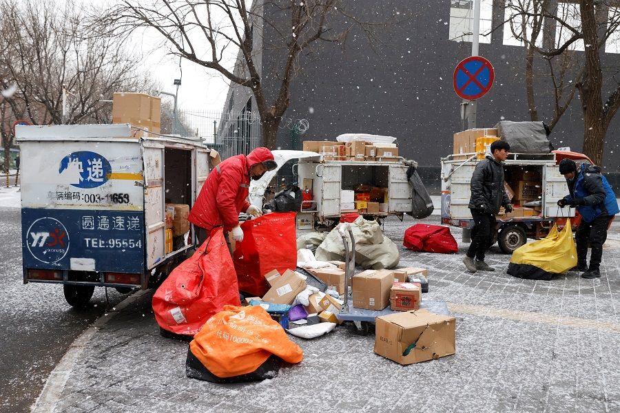 Delivery workers sort parcels amid snowfall in Beijing, China, 20 January 2022. (Carlos Garcia Rawlins/Reuters)
