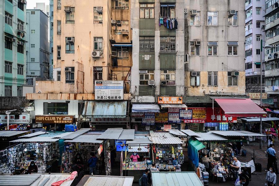 Vendors wait for customers at their street market stalls as residential buildings tower above in Hong Kong, China, on 27 January 2021. (Anthony Wallace/AFP)