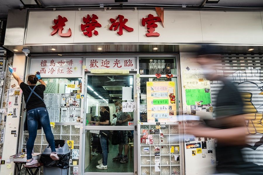 An employee scrapes off stickers and posters with messages supporting the pro-democracy movement from a wall outside a restaurant in Hong Kong. (Lam Yik/Bloomberg)