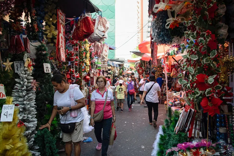 Shoppers walk past shops with Christmas decorations for sale along a street in Manila on 6 December 2024. (Ted Aljibe/AFP)