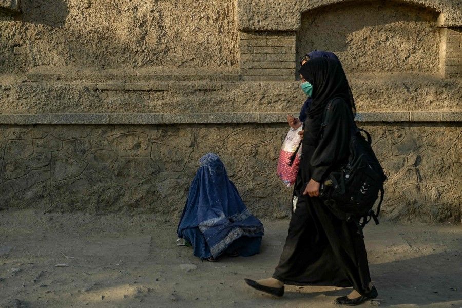 A burqa-clad woman begs for alms from the people passing by a street in Kabul on 26 September 2021. (Hoshang Hashimi/AFP)