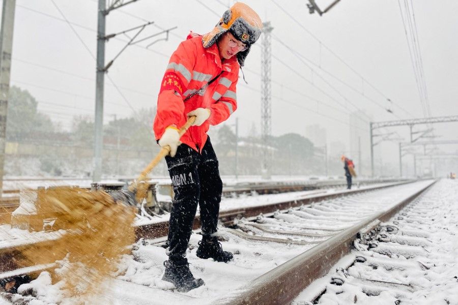 This photo taken on 15 January 2023 shows a railway worker clearing snow from a railroad track during snowfall in Jiujiang, in China's central Jiangxi province. (AFP)