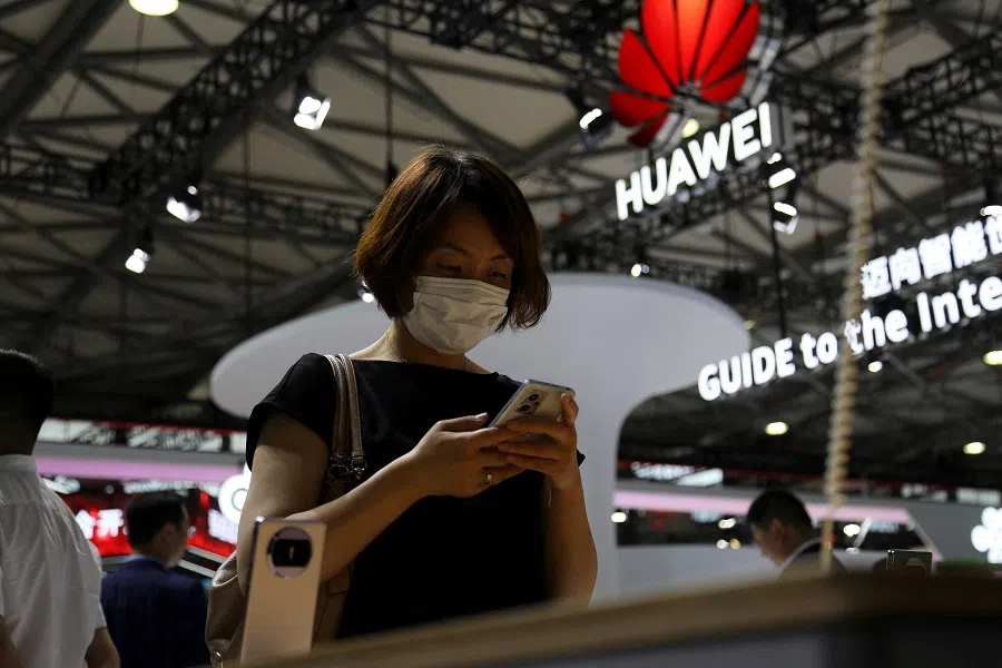 A visitor checks a mobile phone near the Huawei logo during the Mobile World Congress in Shanghai, China, on 28 June 2023. (Nicoco Chan/Reuters)