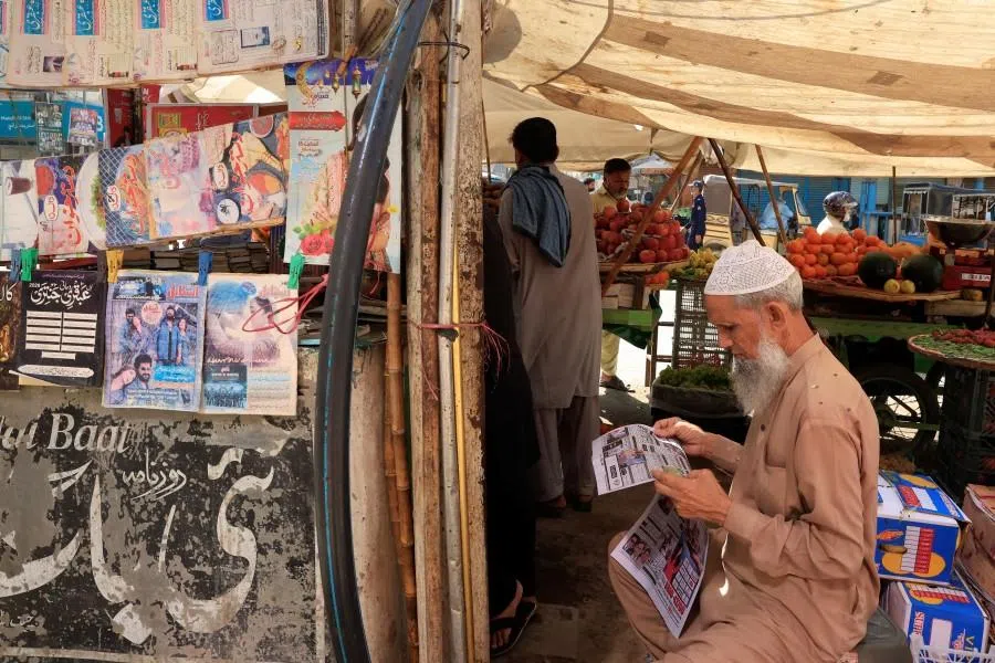 A man reads a newspaper, following the news of exchanges of fire between Pakistan and Afghanistan forces, at a stall along a market in Karachi, Pakistan, 27 February 2026. (Akhtar Soomro/Reuters)
