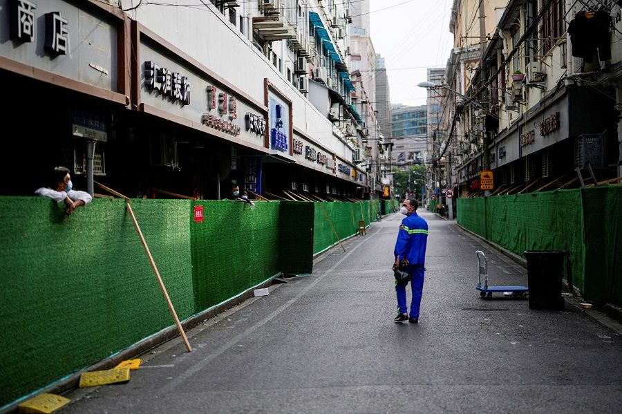 A worker walks at a closed residential area during lockdown, amid the Covid-19 outbreak, in Shanghai, China, 18 May 2022. (Aly Song/File Photo/Reuters)