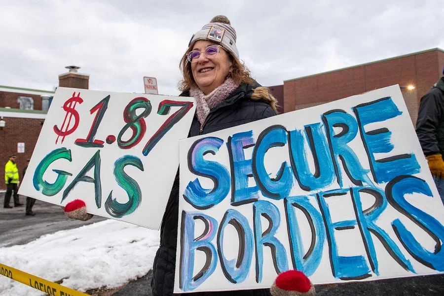 A Trump supporter holds signs during the primary outside a polling site in Hampton, New Hampshire, on 23 January 2024. (Joseph Prezioso/AFP)